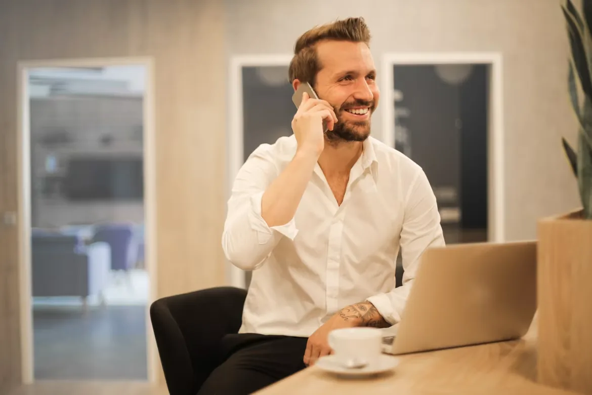 Un dueño de negocio sonriendo mientras habla por teléfono